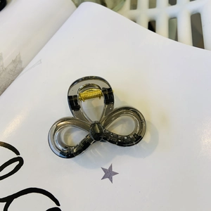 Detail of a dark gray translucent bow hair claw clip with a golden metal spring mechanism