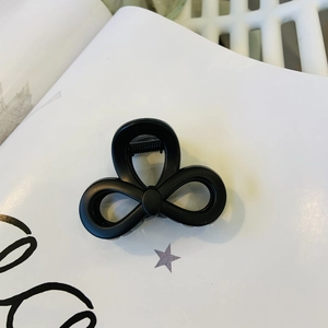 Detailed close-up of matte black triple-loop bow hair claw with durable metal spring