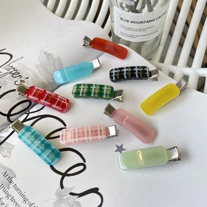 Close-up of colorful checkered and solid hair clips on white magazine background
