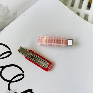 Detailed close-up of red and pink plaid rectangular hair clips on white background