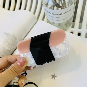 Close-up of tricolor acetate hair claw clip with pink, black, and marble texture finish