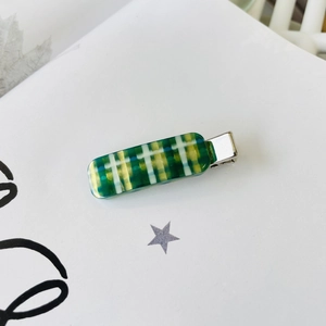 Detailed view of a green and yellow checkered duckbill hair clip with silver metal base
