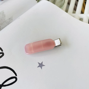 Close-up of a pink rectangular resin hair clip with a silver metal duckbill base
