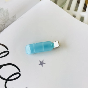 Detail of a rectangle lake blue resin hair clip with segment texture and metal crocodile grip