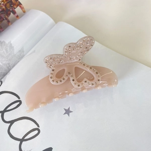 Pince à cheveux papillon élégante en acétate rose avec strass champagne sur magazine