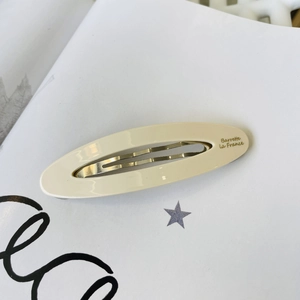 Detailed macro view of cream acetate hair clip with golden Barrette La France lettering