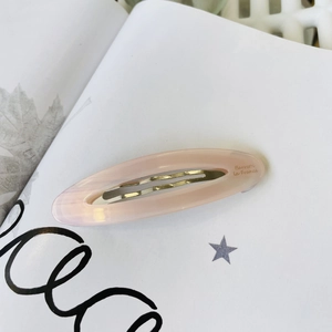 French vintage pink acetate oval hair clip on an open book for an elegant fashion style