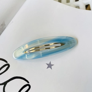 Detail of French acetate hair clip with blue marble texture and gold metal spring