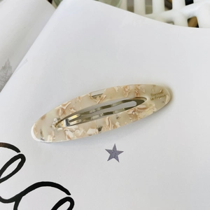 Detail of French acetate oval hair clip with beige marble texture and metal snap