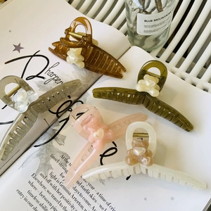 Detail view of five assorted bear claw clips in amber, green, grey, pink and cream white
