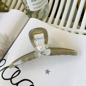 Close-up of translucent olive green hair claw clip with a cute white frosted bear decor