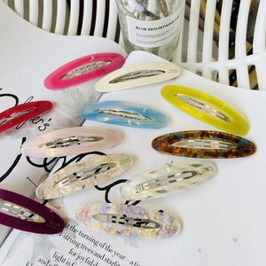 Macro view of colorful oval acetate hair clips showing diverse marble textures and metal clips