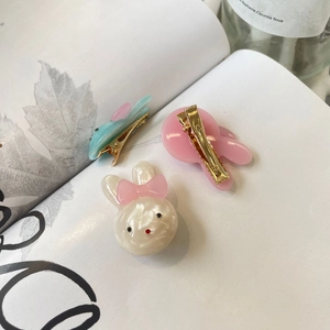 Detailed close-up of cute rabbit and fish hair clips with metal alligator grip design
