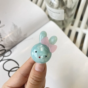 Close-up of a mint green bunny hair clip with a pink bow and jelly resin finish
