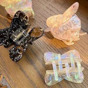 Detail of four acetate butterfly hair claws with LOVE rhinestones and marble patterns