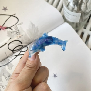 Detailed close-up of blue and purple marble dolphin hair clip held in hand
