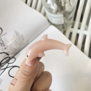Detailed view of a glossy pink dolphin-shaped hair clip with smooth resin surface