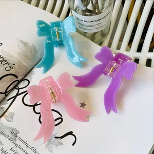 Détail de trois pinces à cheveux en forme de ruban rose, violet et bleu, texture gelée