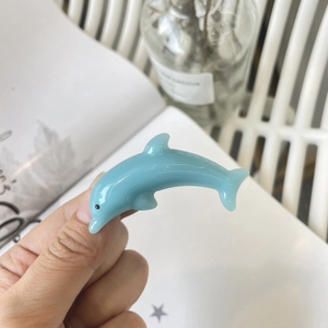 Detail of a sky blue dolphin-shaped hair clip with a smooth glossy resin finish