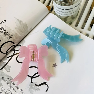 Détail des pinces à cheveux en acrylique rose et bleu clair en forme de ruban avec ressort