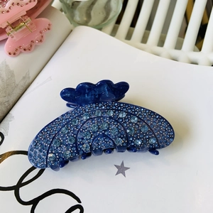 Blue acetate hair claw clip with rhinestones shown on a white magazine background