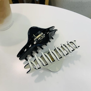 French style hair claws in black and cream white finish on a minimalist background