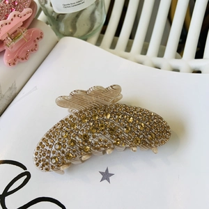 Detailed view of champagne rhinestone claw clip on a white page for hair styling