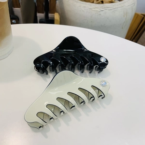 Macro detail of high-gloss acetate hair claws with delicate rhinestone flower accents