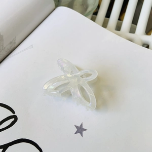 Dettaglio della molletta per capelli a farfalla perlata su una pagina di libro