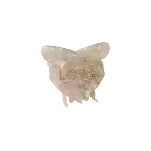Elegant acetate hair claw clip with heart bow design and rhinestone LOVE lettering in pink