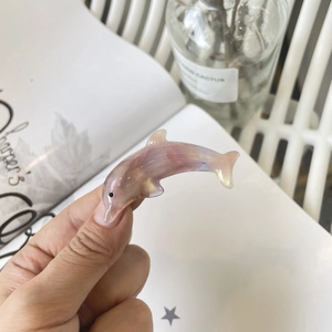 Pearlescent dolphin hair clip with pink purple gradient effect held in hand