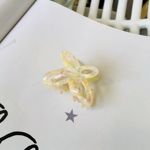 Dettaglio macro di elegante molletta per capelli a farfalla in acetato effetto marmo