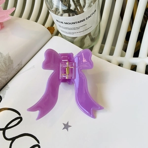 Pince à cheveux élégante en forme de nœud violet sur un fond minimaliste moderne