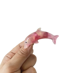 Pink translucent resin dolphin hair clip with glitter details on a plain background