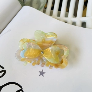 Bow hair claw clip with marble acetate texture and rhinestone accent for elegant styling