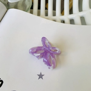 Dettaglio macro di un fermaglio per capelli in acetato viola marmorizzato a farfalla