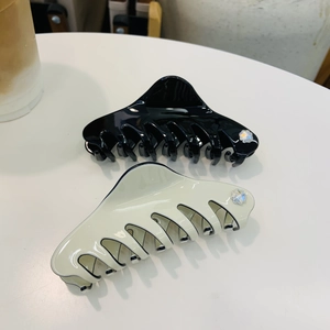Detail of black and beige acetate shark hair clips with rhinestone flower accents