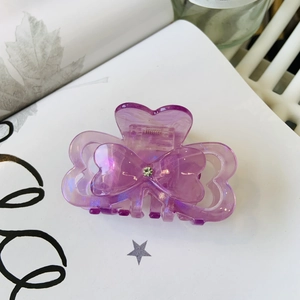 Macro view of purple iridescent acetate claw clip with delicate rhinestone bow detail
