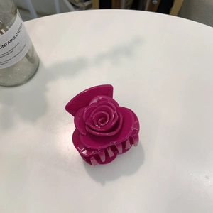 Vue détaillée d'une pince à cheveux en acrylique en forme de rose avec des pétales brillants