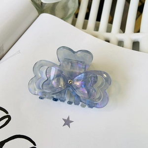 Detailed macro view of heart-shaped acetate claw clip with aurora pearl finish and crystal