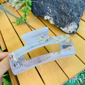 Detail of blue marble ink painting hair claw with white plum blossom and calligraphy