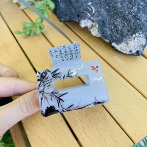 Detail of square hair claw clip featuring blue ink landscape and calligraphy print