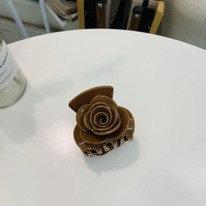 Détail d'une pince à cheveux fleurie en acrylique marron foncé avec finition brillante