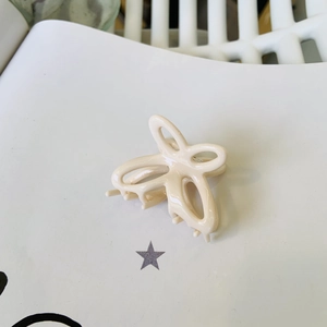 Dettaglio macro della molletta per capelli a farfalla in acetato bianco crema con molla