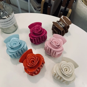 Gros plan détaillé de six pinces à cheveux en forme de rose sur une surface blanche