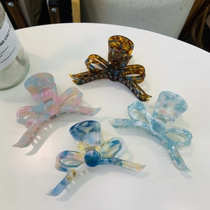 Detailed view of large acetate bow hair claws in four elegant marble patterns and colors
