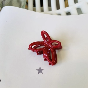 Dettaglio di una molletta per capelli a farfalla rosso scuro lucido con molla in metallo