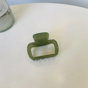 Detailed top view of a green acetic acid square hair claw clip with golden text logo