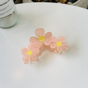 Chic pink acrylic flower hair claw clip with yellow centers on a clean white surface