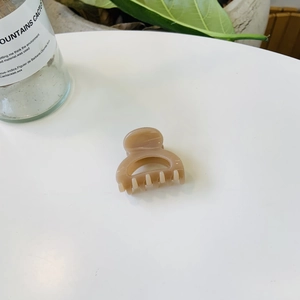Gros plan sur la pince à cheveux minimaliste crème pour la coiffure sur un bureau blanc